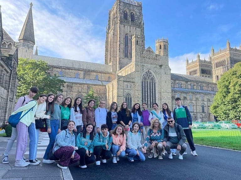 Students on the green in front of Durham Cathedral on a summer day