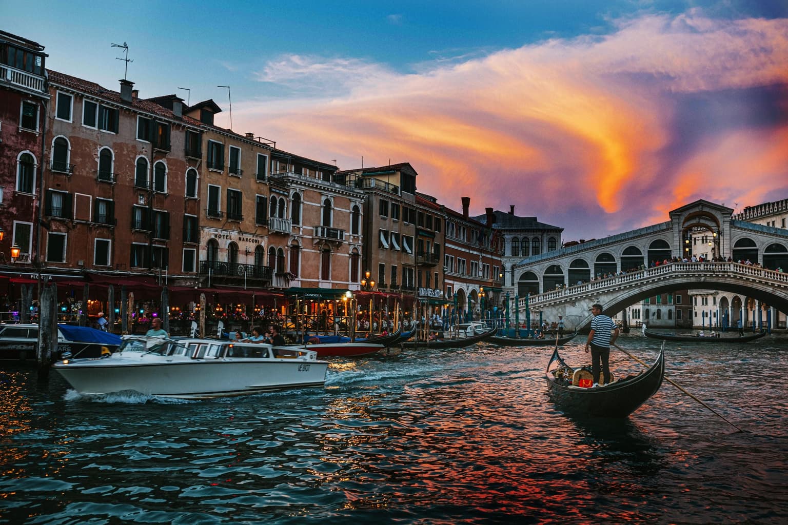 A gondola on the Grand Canal in Venice beside the Rialto Bridge at sunset